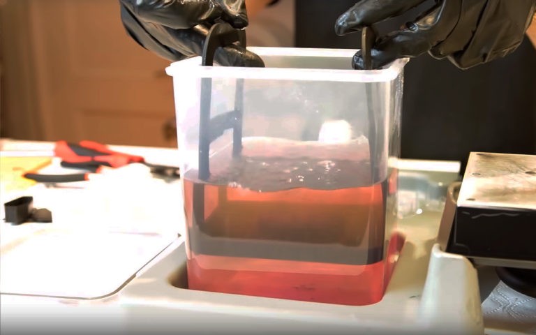 An SLA print being washed by repeatedly dunking the model in a warm isopropyl alcohol bath.